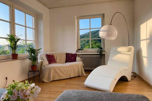 uma sala de estar com duas cadeiras brancas e janelas em Grüne Wohlfühloase mit einmaliger Aussicht em Königswinter