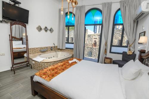 a bedroom with a bed and a tub and windows at Shirat Hayam Boutique Hotel in Tiberias