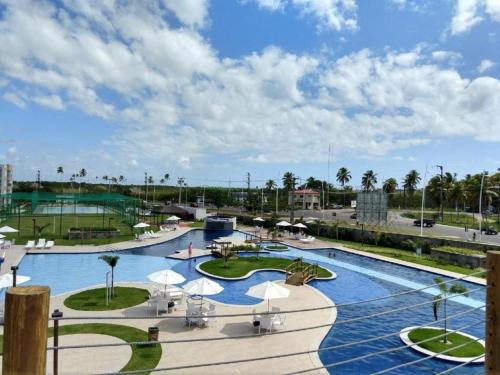 ein großer Pool mit Sonnenschirmen und ein Resort in der Unterkunft Porto de Galinhas, Flat em Muro Alto Condomínio Clube in Ipojuca