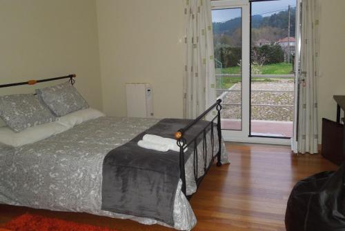 a bedroom with a bed and a large window at Casa das Bocelinhas in Arouca