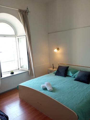 a bedroom with a bed with a blue blanket and a window at Rooms Zela 1 in Korčula