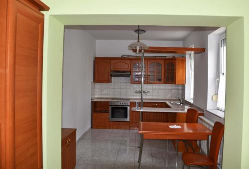 a kitchen with wooden cabinets and a table and a dining room at Pilikán Apartments Lenti in Lenti