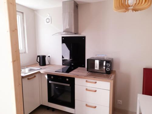 a small kitchen with a microwave and a stove at Résidence Mirage avec vidéo surveillance in Albertville