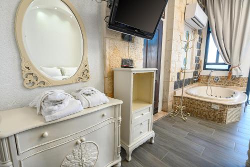 a bathroom with a mirror and a sink and a tub at Shirat Hayam Boutique Hotel in Tiberias