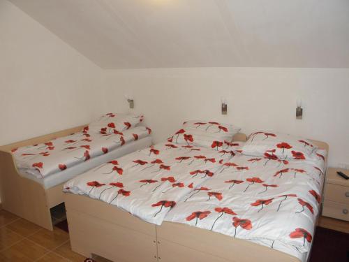 a bedroom with two beds with red flowers on them at Hotel and Restaurant Ana in Hrib-Loški Potok
