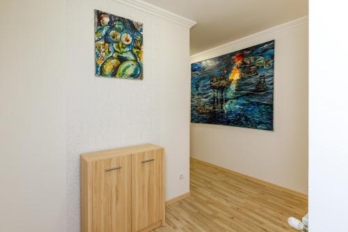a room with two paintings on the wall and a wooden cabinet at Andi Apartman in Hévíz