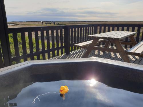 un canard en caoutchouc dans une piscine sur une terrasse avec une table de pique-nique dans l'établissement Ocean Break Cabins, à Sandgerði