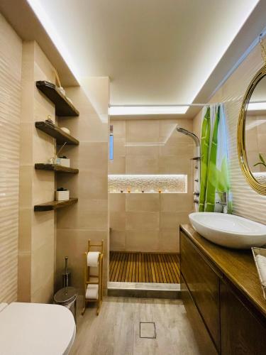 a bathroom with a sink and a toilet and a mirror at Kapsalakis Penthouse in Korinthos