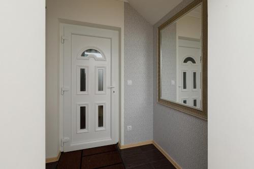 a hallway with a white door and a mirror at Andi Apartman in Hévíz
