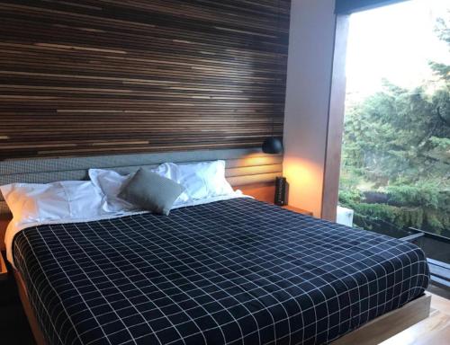 a bedroom with a bed with a checkered blanket and a window at Winter Suites Campos do Jordão - Capivari in Campos do Jordão