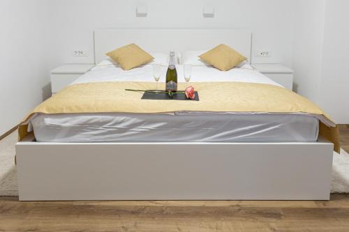 a large white bed with a bottle of wine on it at ININ APARTMENTS in Bled