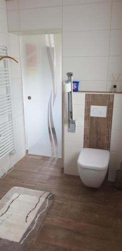 a white bathroom with a toilet and a rug at Ferienwohnung Hillig in Elterlein
