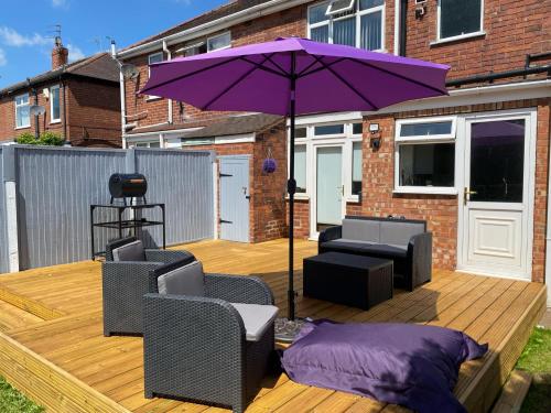 a purple umbrella sitting on a wooden deck with chairs at The Homestead House in Doncaster