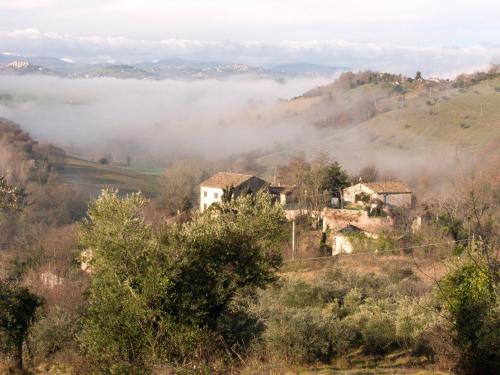 a house on a hill with fog in the valley at B&B La Cappellania in Montegiorgio