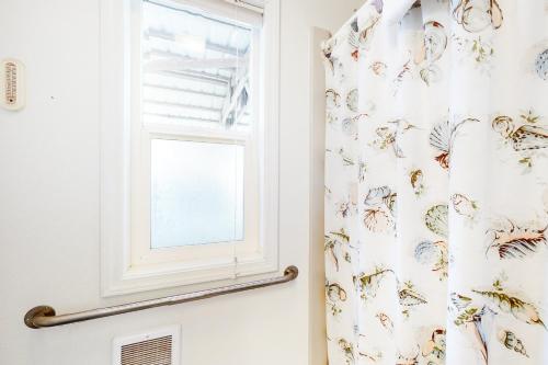 a bathroom with a shower curtain with a window at Enjoy the View in Waldport
