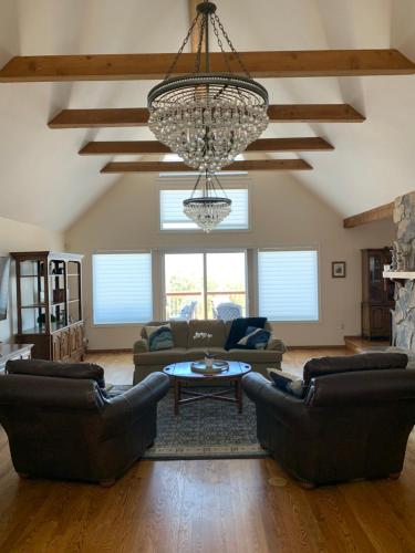 a living room with couches and a chandelier at Villa Alta Vista at Yosemite- Stunning Views and Game Room in Mariposa