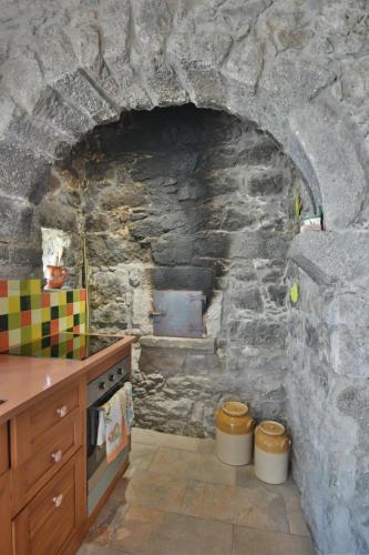 a kitchen with a stone wall with a oven at Charming green country house in Laseira