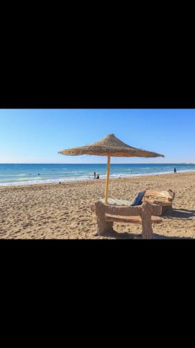 a beach with an umbrella and a chair on the sand at Cozy sunny ground chalet with terrace-Ras Sudr in Ras Sedr