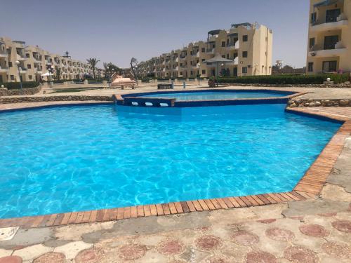 a swimming pool with blue water in front of some buildings at Cozy sunny ground chalet with terrace-Ras Sudr in Ras Sedr