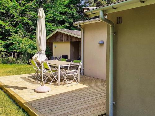 una terraza de madera con mesa y sombrilla en 4 person holiday home in Frederiksv rk, en Frederiksværk