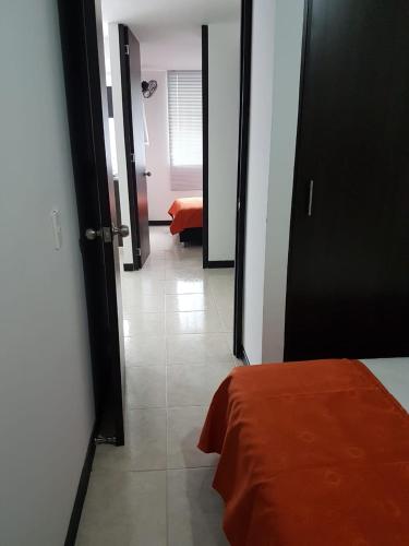 a room with a bed and a hallway with a door at Economico Apto a 3' al Parque del Café in Quimbaya