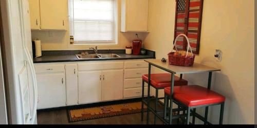 uma cozinha com armários brancos, um lavatório e bancos em Cute Shouse Unit 2 em Ozark