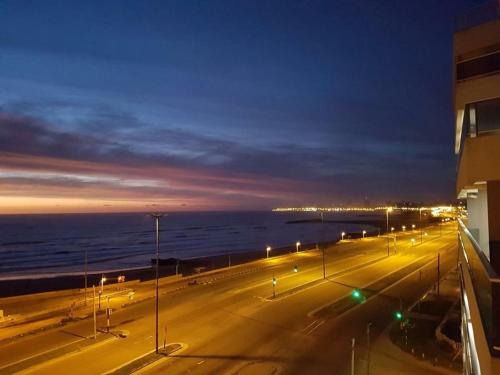 a street with street lights and the ocean at night at Departamentos Eneas Frente al Mar in Mar del Plata