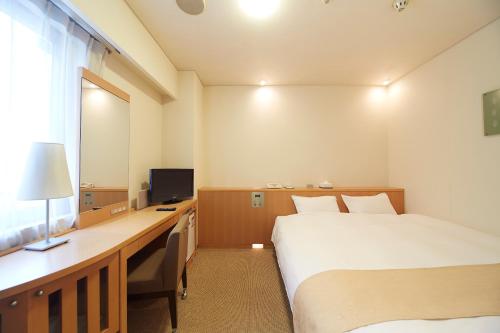 a hotel room with a bed and a desk with a computer at Nest Hotel Kumamoto in Kumamoto
