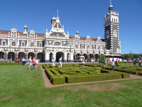 a large building with a clock tower and a garden at Rosemount B&B by the Sea St Clair in Dunedin