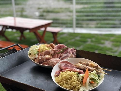 two bowls of food on a table with noodles and meat at Ｖｉｌｌａ・Ｃｈａｒｍｅ in Motobu