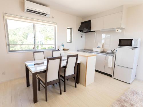 a kitchen and dining room with a table and chairs at Ｖｉｌｌａ・Ｃｈａｒｍｅ in Motobu