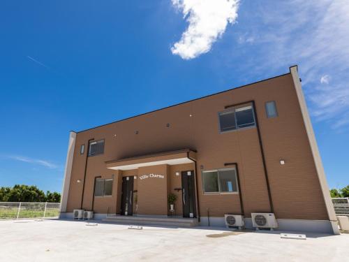 a large brown building with two chairs in front of it at Ｖｉｌｌａ・Ｃｈａｒｍｅ in Motobu
