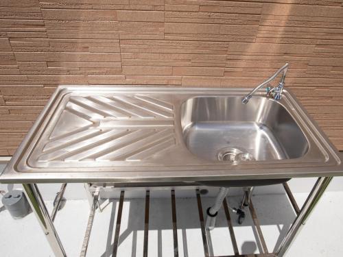 a stainless steel sink in a room with a wall at Ｖｉｌｌａ・Ｃｈａｒｍｅ in Motobu
