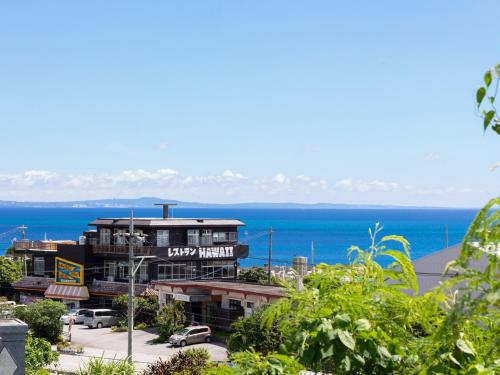 a view of a building with the ocean in the background at Ｖｉｌｌａ・Ｃｈａｒｍｅ in Motobu