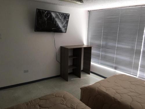 a bedroom with a bed and a table and a window at Estadía El Dorado in Bogotá