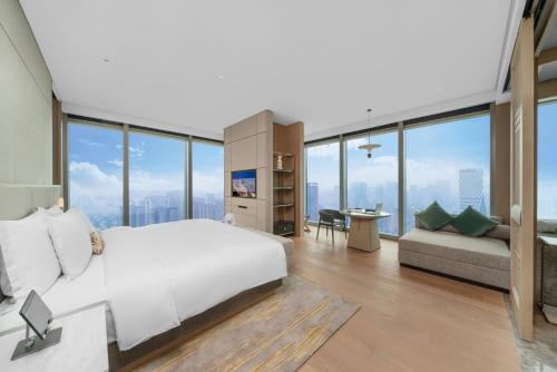 a bedroom with a large white bed and a couch at Grand Bay Hotel Chengdu in Chengdu