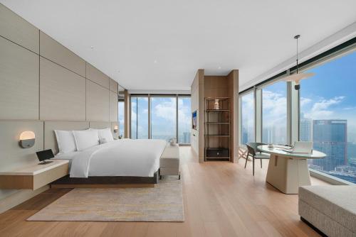 a bedroom with a large bed and a desk and a desk at Grand Bay Hotel Chengdu in Chengdu