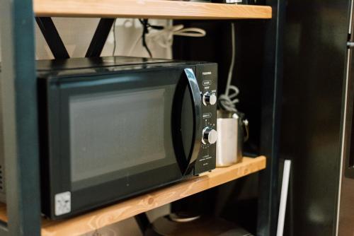 a black microwave oven sitting on a shelf at Plage in Yamada