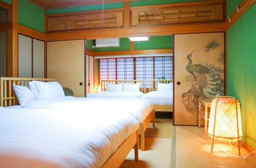Habitación con 2 camas y una pintura de pavo real en la pared. en かわもと別邸３４６６, en Yufu