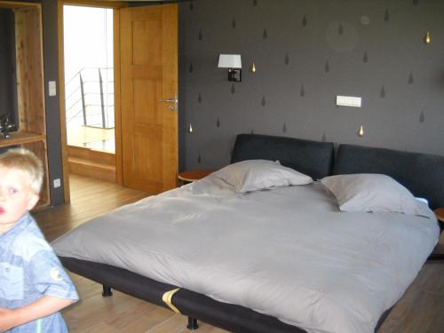 a boy standing next to a bed in a room at À la Belle Vue in Limbourg