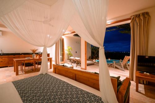 a bedroom with a canopy bed with a view of the ocean at Sumberkima Resort in Pemuteran