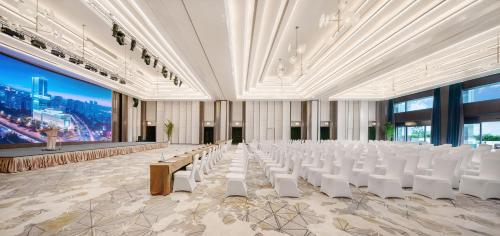 a large room with white chairs and a large screen at Grand Bay Hotel Chengdu in Chengdu