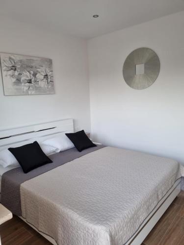a white bedroom with a large bed with black pillows at Angel wing apartmant in Duće