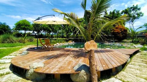 a wooden table with an umbrella next to a pool at 豐 FONG PENSiON - 無合作 ᴀɢᴏᴅᴀ 平台 in Taitung City