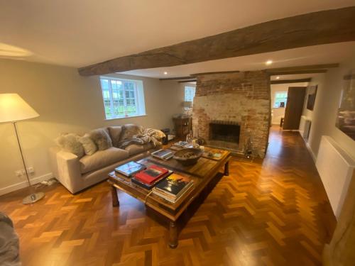 a living room with a table and a fireplace at Charlton End - Goodwood Events in Chichester