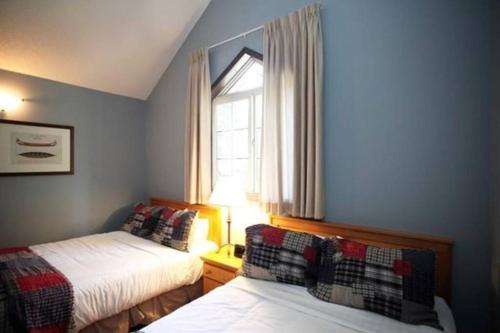 1 dormitorio con 2 camas y ventana en Delightful Chalet 2BD 2BA Pool Hot Tub BBQ Private Entry Park Pass, en Canmore