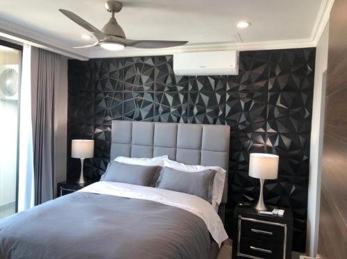 1 dormitorio con 1 cama grande y pared negra en JF Apartments, en Tegucigalpa