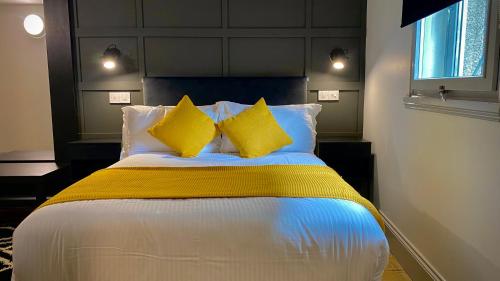 a bedroom with a bed with yellow and white pillows at Siberia Bar & Hotel in Aberdeen