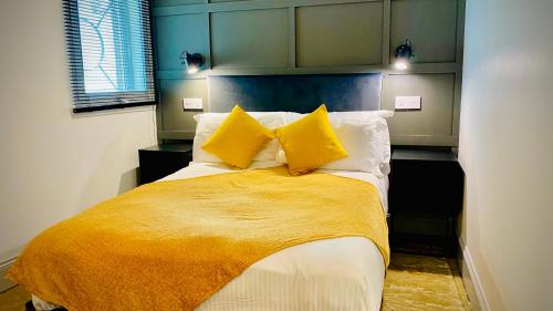 a bedroom with a bed with yellow sheets and pillows at Siberia Bar & Hotel in Aberdeen