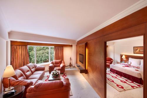 a living room with a couch and a bed at Accord Highland Hotel Ooty in Ooty